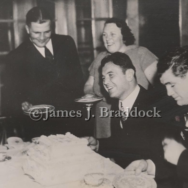 Jim and his sparring partner, Jack McCarthy(right), take a break from training for the Louis fight to enjoy some cake at the home of Mr. and Mrs. Karl Ogren. Lake Shishebogama in northern Wisconsin. 4/6/1937.
