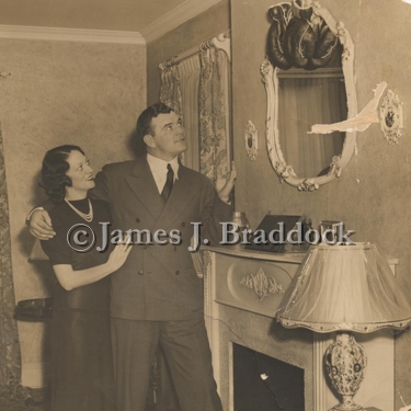 Mae & Jim Braddock look at a pair of the Champ's boxing gloves hanging over the fireplace in their North Bergen home.