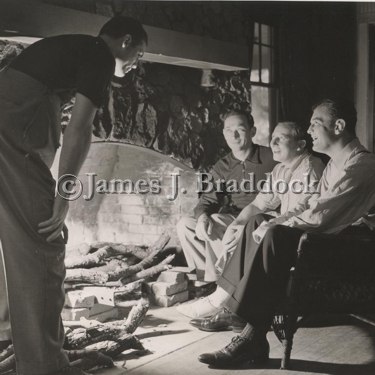 Sparring partner Jack McCarthy, Trainer Doc. Robb, Manager Joe Gould, and Jim Braddock keeping warm by the fire. Camp Kenosha, Wiss. 6/20/1937.